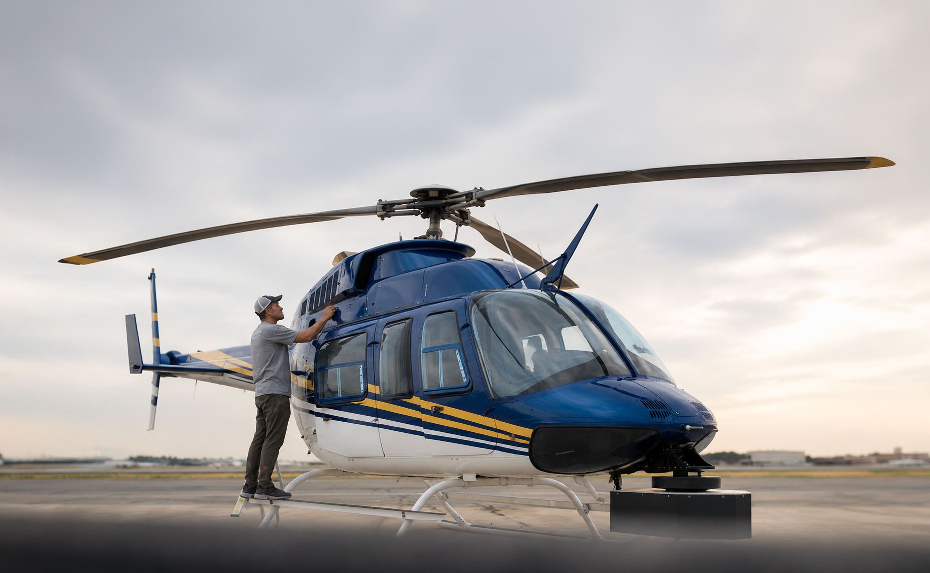 Technician inspecting a blue helicopter equipped with aerial LiDAR sensors